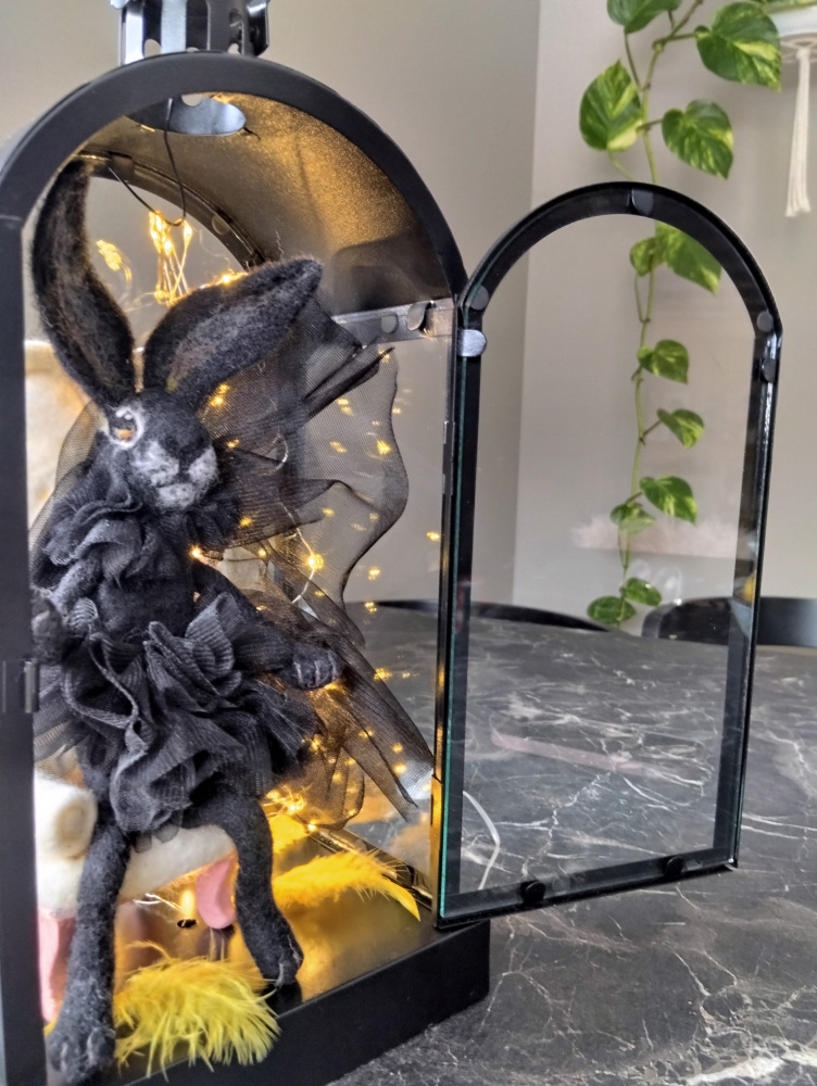 Souvenir Black Rabbit symbol of 2023, in vain by dry method.consists of: rabbit, chair, light bulbs, metal lantern.the rabbit is dressed in tulle  